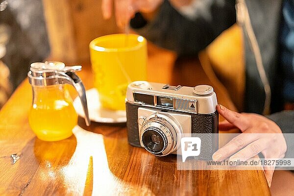 Die Hand eines Touristen mit einer Fotokamera bei einem Tee in einer Cafeteria