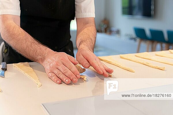 Detail der Hände eines Mannes beim Backen von Croissants  Formgebung mit dem Blätterteig  Arbeit zu Hause