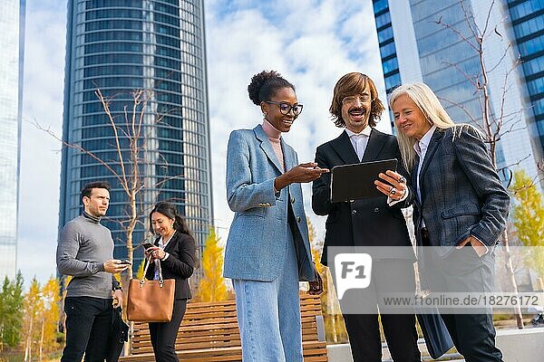Multiethnische Geschäftskollegen oder Führungskräfte  die sich mit Technologie und gläsernen Bürogebäuden befassen