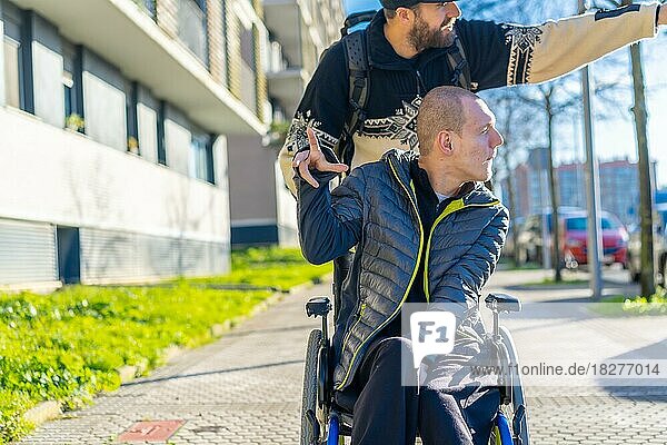 Behinderte Person im Rollstuhl lacht mit einem Freund im Rollstuhl auf der Straße im Winter