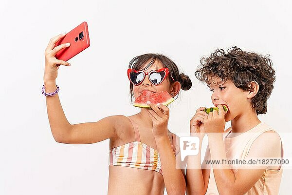 Kinder genießen den Sommer  essen eine Wassermelone und machen ein Selfie mit dem Telefon. Weißer Hintergrund