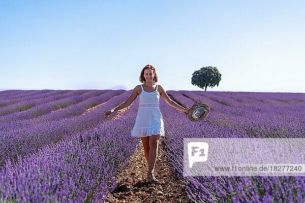 Lebensstil einer lächelnden Frau in einem sommerlichen Lavendelfeld  die ein weißes Kleid trägt