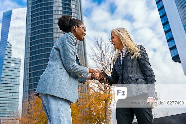 Multiethnische Geschäftsfrauen und Führungskräfte  lächelnd und sich die Hände schüttelnd in einem Gewerbegebiet