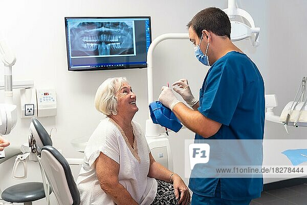 Zahnklinik  Zahnarzt  der sich mit einer älteren Frau amüsiert  die auf dem Tisch liegt