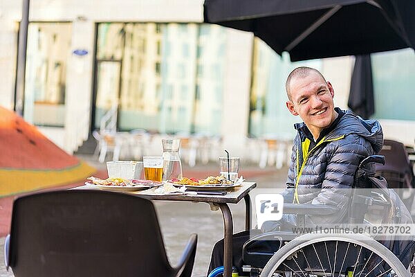 Eine behinderte Person im Rollstuhl in einem Restaurant lächelt und hat Spaß