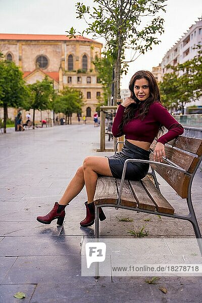 Brünette Frau im Lederrock sitzend in der Stadt  Lifestyle  Mode-Pose  vertikales Foto