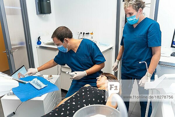 Zahnklinik  Zahnarzt und Assistentin führen einen 3D-Scan des liegenden Patienten durch