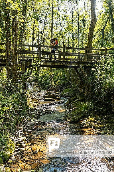 Eine Mutter mit ihrem Sohn im Rucksack überquert eine Holzbrücke im Pagoeta-Park in Aia  Guipuzcoa  Baskenland  Spanien  Europa