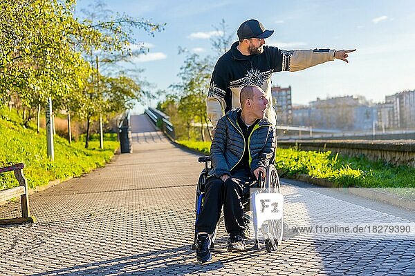 Eine behinderte Person im Rollstuhl mit einem Assistenten bei einem Spaziergang durch die Stadt