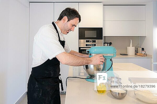 A man baker cooking a red velvet cake at home  preparing the cake in the kitchen robot  work at home