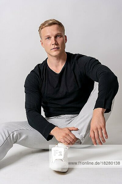 Caucasian blonde model in a black sweater on a white background  staring at the camera