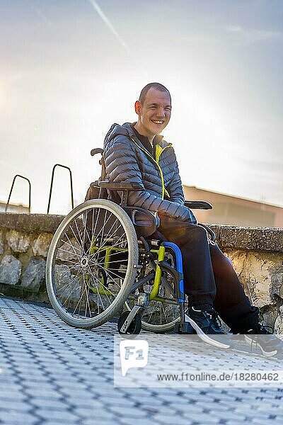 Porträt einer behinderten Person im Rollstuhl  die sich bei Sonnenuntergang in einem Park amüsiert