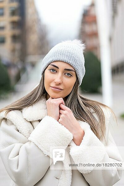 Winterporträt einer kaukasischen Frau mit Wollmütze in der Stadt  die in die Kamera schaut