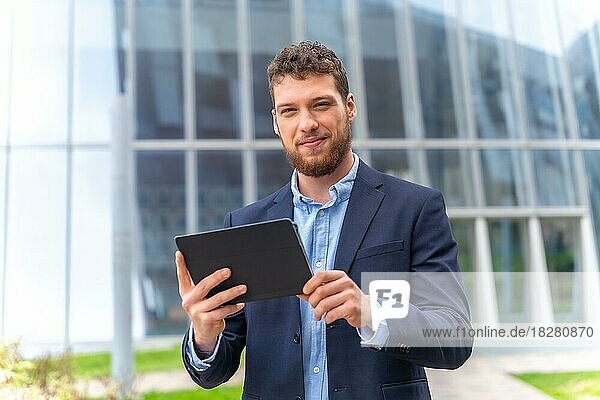 Porträt eines jungen männlichen Geschäftsmannes oder Unternehmers außerhalb des Büros  mit einem Tablet in der Hand