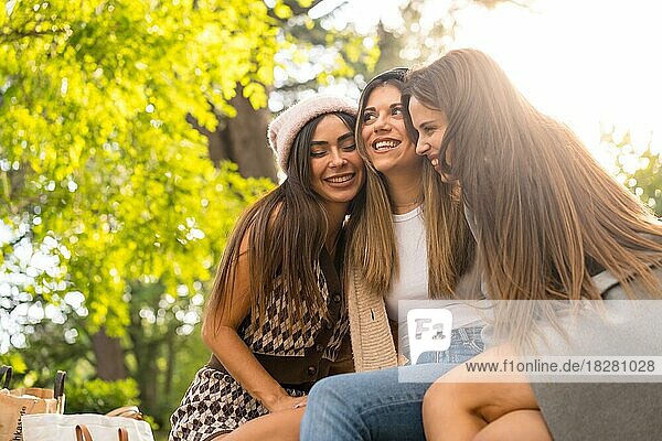 Women friends sitting hugging in a park in autumn at sunset  autumn lifestyle
