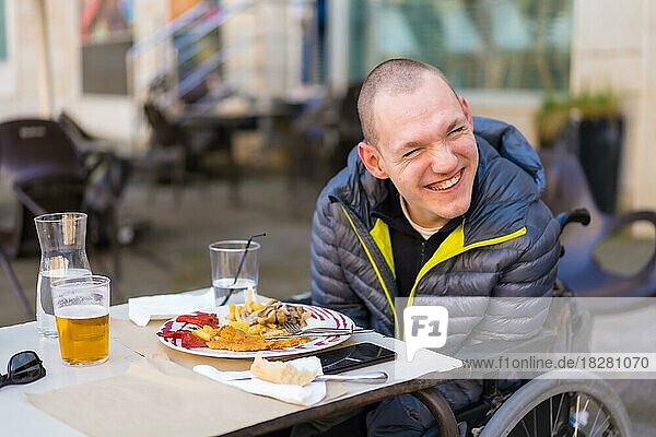 Porträt einer behinderten Person im Rollstuhl in einem Restaurant  die lächelt und Spaß hat