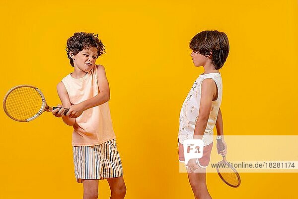 Zwei Brüder spielen Tennis und haben Spaß im Sommer  gelber Hintergrund