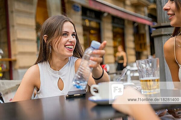 Frau mit Freunden  die an einem Nachmittag mit ihren Freunden auf der Terrasse einer Cafeteria etwas trinken
