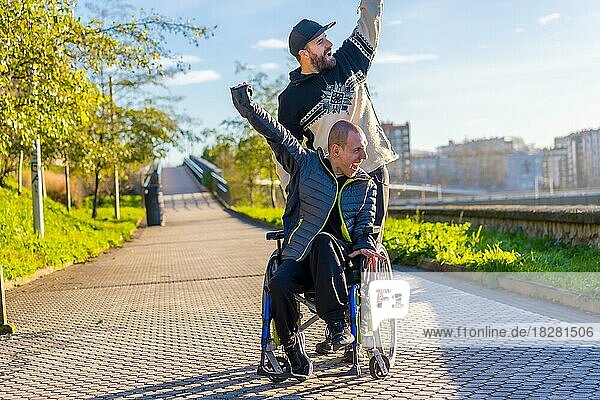 Disabled person in wheelchair with friend overjoyed  smiling  enjoying with arms up  vistoria  enjoying life