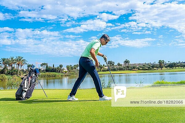 Male golf player on professional golf course. Golfer with golf driver stick preparing the shot