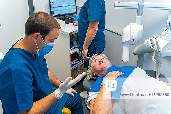 Zahnklinik  Zahnarzt und Assistentin erläutern einer älteren Frau die zahnärztliche Untersuchung