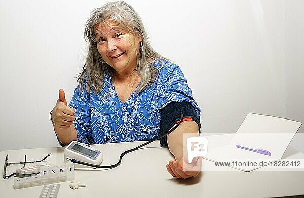 Woman taking her blood pressure with a nod of approval everything ok