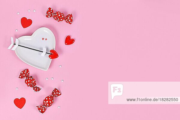 Nette Valentinstag Süßigkeiten  herzförmige Platte und Liebe Pfeile auf rosa Hintergrund mit Kopie Raum