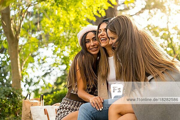 Women friends sitting hugging in a park in autumn at sunset  lifestyle and autumnal outfit
