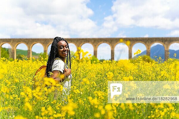 Genießen Sie den Frühling im Urlaub  schwarze ethnische Mädchen mit Zöpfen  Reisende  in einem Feld von gelben Blumen