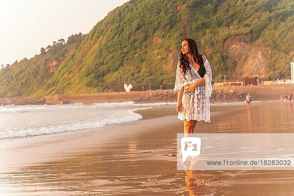 Porträt einer Frau in einem weißen Kleid bei Sonnenuntergang  die ihren Urlaub am Strand genießt