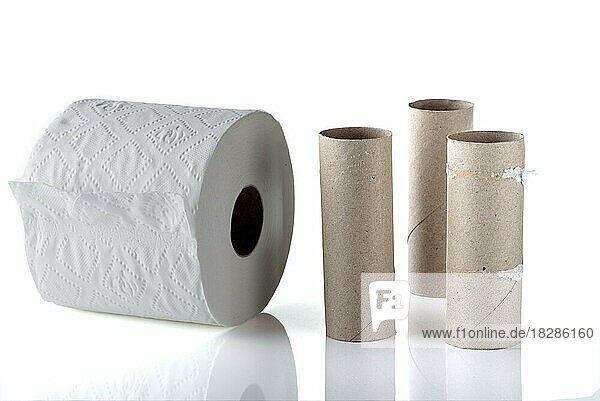 Drei leere Toilettenpapierrollen neben einer neuen vollen Rolle