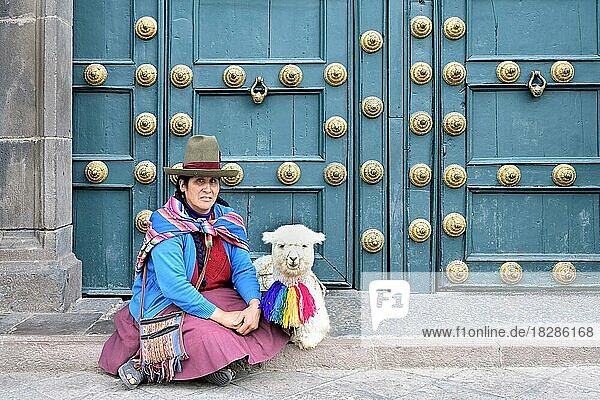 Einheimische Frau sitzt mit einem Lama vor der Eingangstür der Basilika La Merced  Cusco  Peru  Südamerika