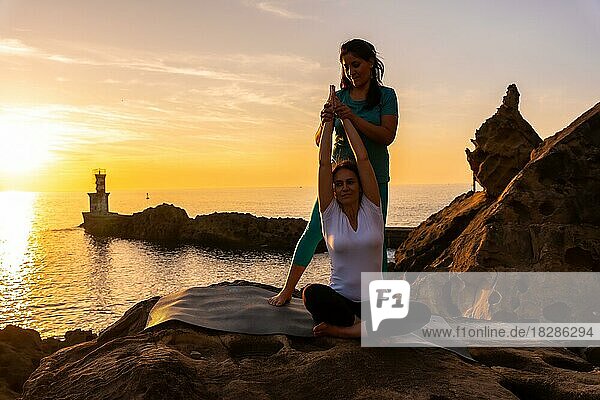 Ein Yogalehrer arbeitet mit den Schülern in der Natur am Meer bei Sonnenuntergang  gesundes und naturistisches Leben  Pilates im Freien