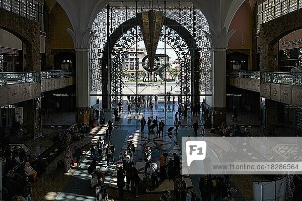 Light entering through the entrance portal  passers-by  crowd in the station concourse  view from above  backlight  interior shot  Marrakech railway station  Morocco  Africa