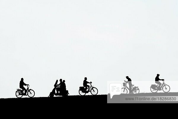 Motorroller  der an Radfahrern vorbeifährt  und ein Mann auf dem Fahrrad  der im Sommer sein Smartphone überprüft  vor einem weißen Hintergrund