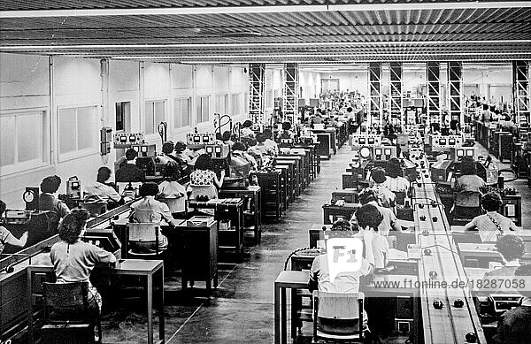 Altes Schwarz-Weiß-Archivfoto  das Arbeiterinnen bei der Herstellung kleiner Elektromotoren in einer Fabrik in den 1950er Jahren zeigt