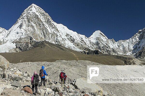 Wanderer beim Überqueren der Gletschermoränen auf dem Weg zum Everest-Basislager in der Nähe von Gorakshep im Khumbu-Tal in der Everest-Region. Der Pumori befindet sich auf der linken Seite und der Kala Patthar  einer der besten Aussichtspunkte im Himalaya  liegt darunter. Khumbu-Region  Sagarmatha-Nationalpark  Solukhumbu  Nepal  Asien