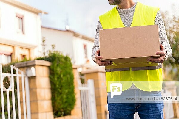 Paketzusteller mit einem Karton eines Online-Shops  der an eine Wohnung geliefert wird