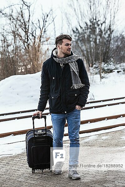 Junger Mann im Winter mit Koffer