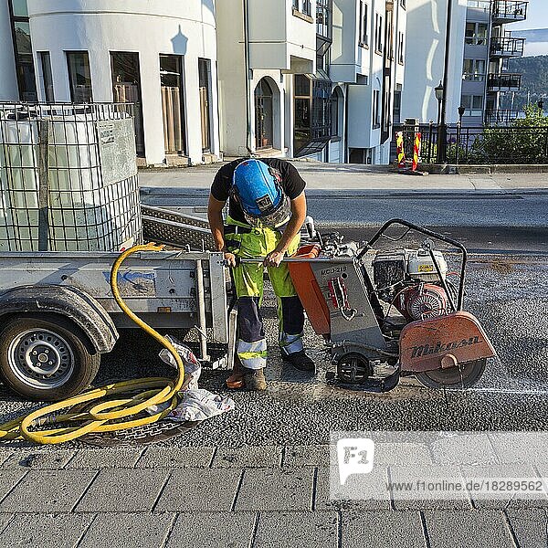 Straßenarbeiter mit Schutzkleidung schneidet Asphalt auf einer Straßenbaustelle  Asphaltschneider  Ålesund  Alesund  Norwegen  Europa