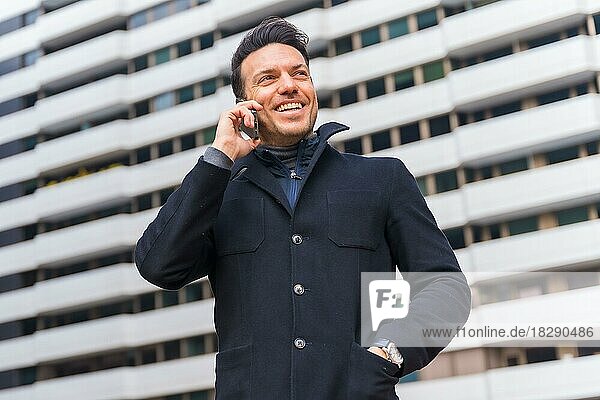 Kaukasischer Geschäftsmann mittleren Alters  der in der Stadt lächelnd telefoniert