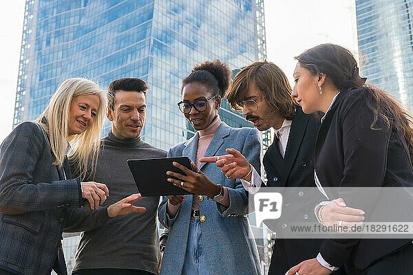 Eine Gruppe lächelnder multiethnischer Geschäftsleute schaut auf eine Tafel vor dem Glasgebäude