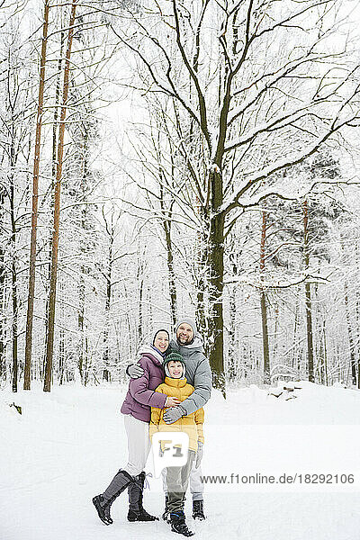 Happy family embracing on snow at winter park