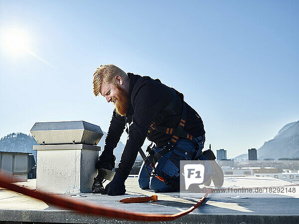 Roofer repairing roof on sunny day