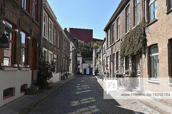 Belgium  West Flanders  Bruges  Empty cobblestone street with rows of town houses on each side