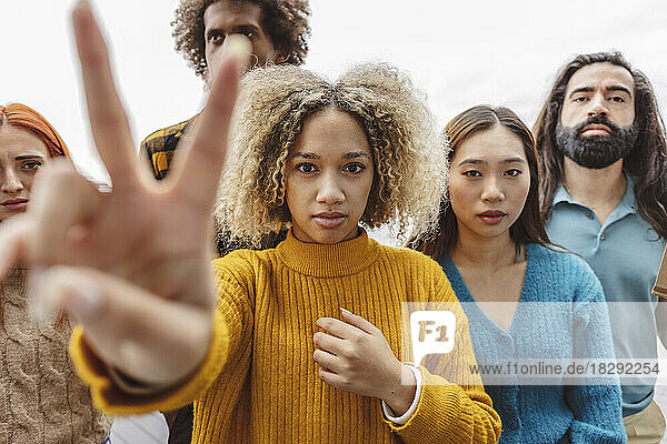 Woman showing peace sign with diverse protestors