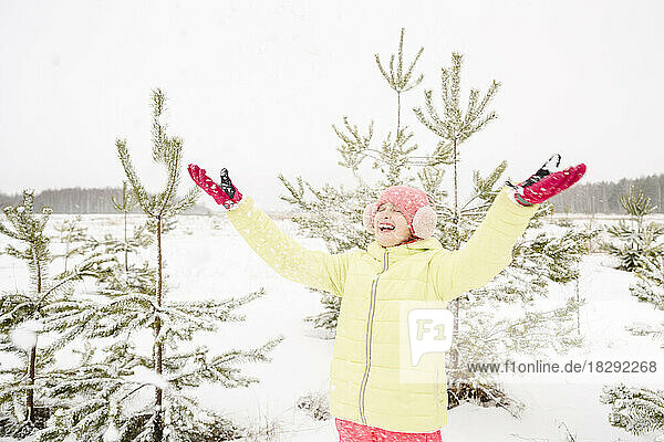 Fröhliches Mädchen  das Schnee wirft und den Winterurlaub genießt