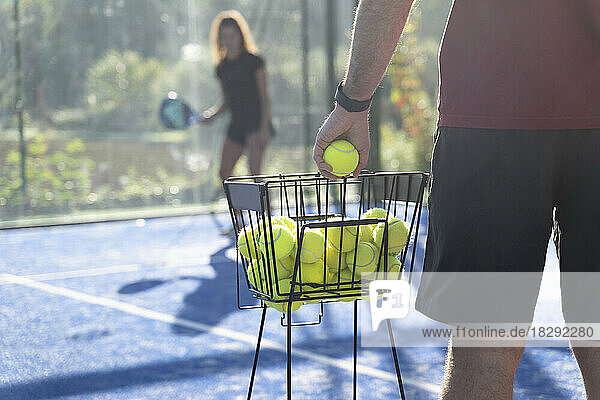 Mann hält Tennisball  Frau steht im Hintergrund
