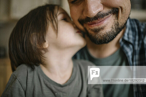 Son kissing father on cheek at home
