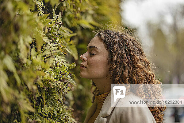 Young woman with eyes closed smelling leaves